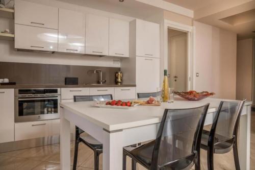 a kitchen with white cabinets and a white island with chairs at Kristal Paris Resort in Novalja
