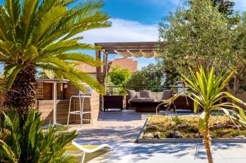 a patio with a couch and a palm tree at Kristal Paris Resort in Novalja