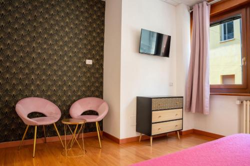 two pink chairs and a tv in a bedroom at LHE Les Trois Merveilles in Cesena