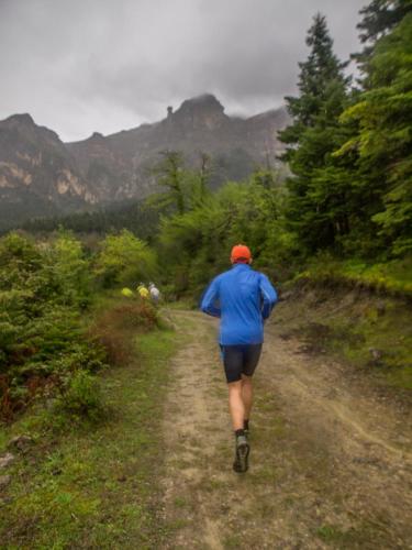 a person running down a dirt road with mountains in the background at Frasta's Rose in Plaka