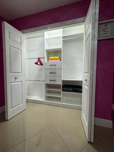 a white closet with purple walls and white doors at Beautiful and comfy home! in Seffner
