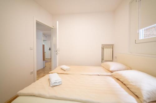 two beds in a white room with towels on them at Four Seasons Apartments in Sarajevo