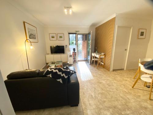 a living room with a black couch and a table at Bimbimbie House Batemans Bay in Surf Beach