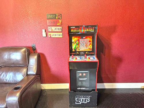 a video game machine in a room next to a couch at Sophisticated 5BR 2,5BA Holiday Villa - Pool Sauna Hot Tub in Grand Prairie