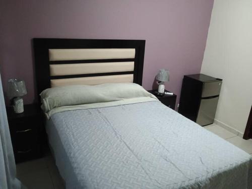 a bedroom with a white bed with two night stands at Tu casa fuera de casa in San Pedro Sula
