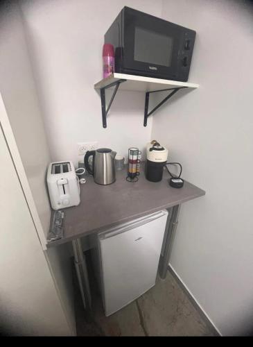 Elle comprend une petite table avec un four micro-ondes et un grille-pain. dans l'établissement Pacha studio, à Bagnolet