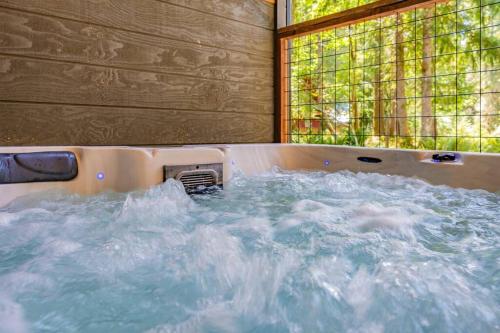 a bath tub filled with water with a window at Luxe Chalet at Rainier Entrance with Hot Tub-AC-WiFi in Ashford
