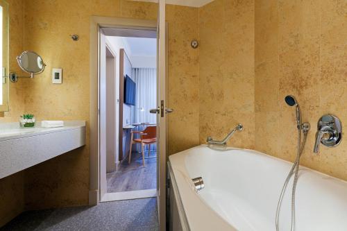 a bathroom with a tub and a sink at Malta Marriott Resort & Spa in St Julian's