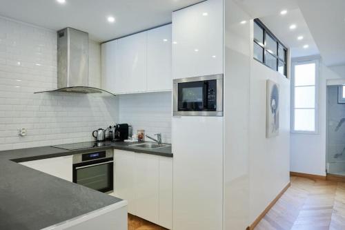 une cuisine blanche avec un évier et un micro-ondes dans l'établissement Appartement type F2 rénové- Quartier Elysée, à Paris
