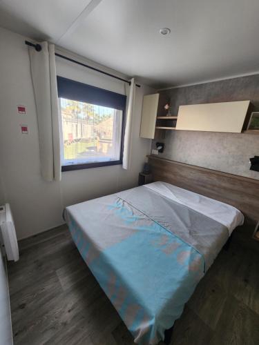 une chambre avec un grand lit avec une fenêtre dans l'établissement Mobil-home climatisé à Valras Plage dans le camping 4 étoiles les Sables du midi à 800m de la plage, à Sérignan
