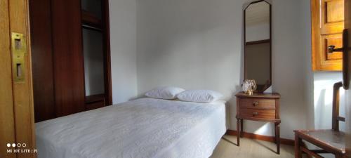 a bedroom with a white bed and a wooden dresser at Casa da Torre in Penela