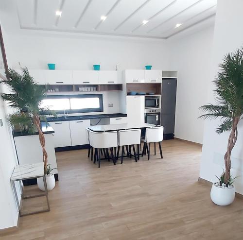 DjerbaにあるVilla avec piscine, 3 suites, 6lits, à 3min de la plageの白いキャビネットとテーブルと椅子のあるキッチン