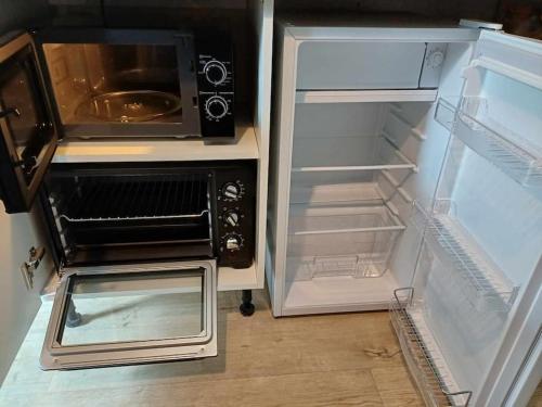 d'un réfrigérateur ouvert avec un four micro-ondes. dans l'établissement Petite maison studio cosy avec jardin, à Saint-Honoré-les-Bains