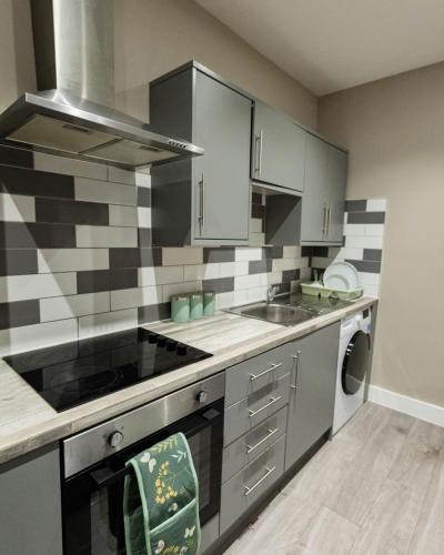 a kitchen with a sink and a stove at Luxury Modern Flat In Wolverhampton- Garden Views in Wolverhampton