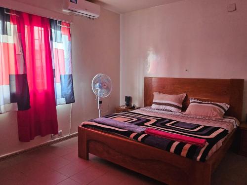 a bedroom with a bed with red curtains and a fan at Villa duchesse in Sali Nianiaral