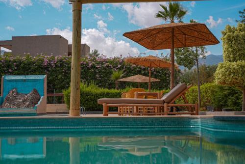a swimming pool with two chairs and an umbrella at RIMALIZ House in Amizmiz