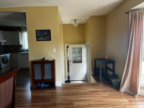 a living room with a wooden floor and a white door at Beautiful room close Airport! in Calgary