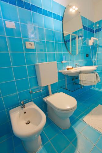 a blue tiled bathroom with a toilet and a sink at Hotel Flora in Milano Marittima