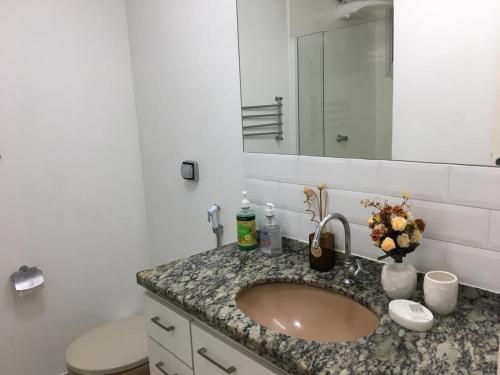 a bathroom with a sink and a toilet and a mirror at Poucos passos do mar na Praia da Costa in Vila Velha