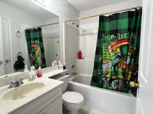 a bathroom with a sink and a toilet and a shower curtain at Hidden valley treehouse home! in Calgary