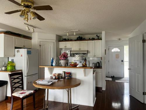 a kitchen with white cabinets and a table in it at Hidden valley treehouse home! in Calgary