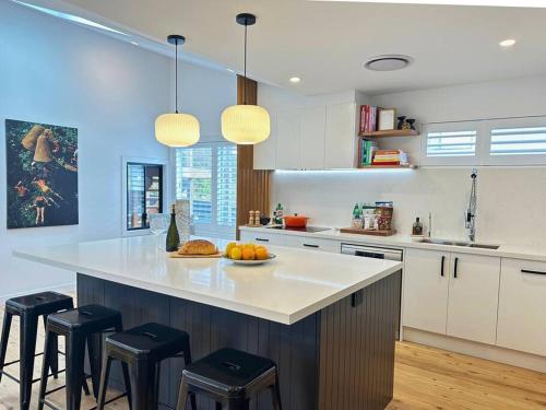 une cuisine avec un comptoir et des tabourets. dans l'établissement Casa Dis Family Friendly 350m walk to beach, à Caves Beach