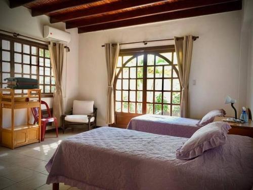 a bedroom with two beds and a chair and a window at The House Of Don Lucho in Santa Cruz de la Sierra
