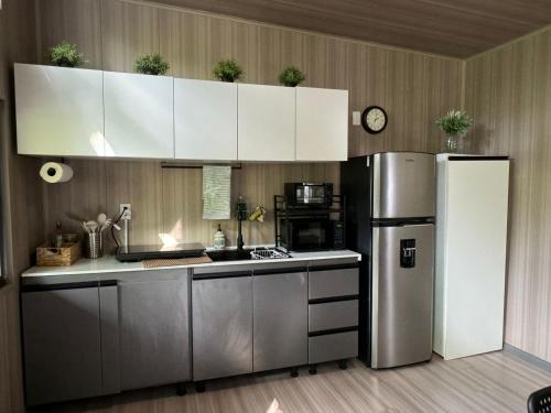 a kitchen with white cabinets and a stainless steel refrigerator at Bungalows at Residencias Arenal in Fortuna