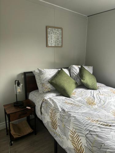 a bedroom with a bed with green pillows on it at Bungalows at Residencias Arenal in Fortuna