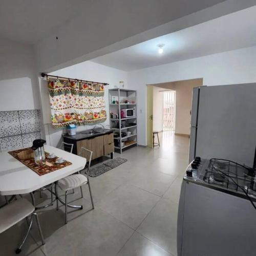 a large kitchen with a table and a refrigerator at Espaço Tranquilo-preço até 4 hóspedes in Pôrto Feliz