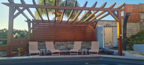 a pool with chairs and a wooden pergola at Les Gîtes Kajou in Bouillante