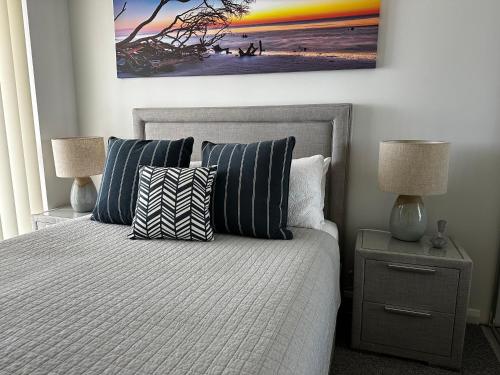 a bedroom with a bed with pillows and a painting on the wall at Broadwater Parklands Paradise in Gold Coast