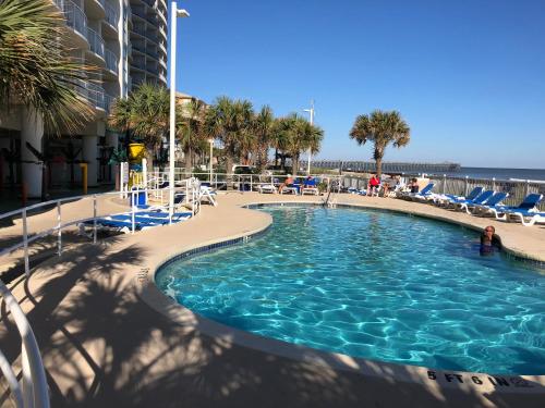 a swimming pool with chairs and the ocean in the background at Sandy Beach Resort in Myrtle Beach