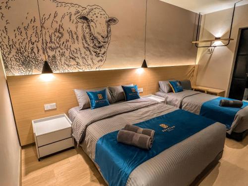 two beds in a room with a picture of a sheep on the wall at Hotel Brynton at Cameron Centrum Mall in Cameron Highlands