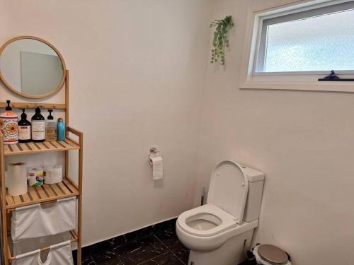 a bathroom with a toilet with a mirror and a window at Auyea Farm 3BR Entire House - 7 Mins to Gumbuya World in Tynong North