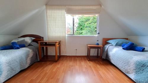 two beds in a room with a window and wooden floors at Cómodo, acogedor, gran ubicación y desayuno sureno in Osorno