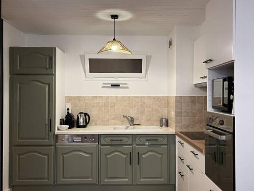 une cuisine avec un évier et un micro-ondes dans l'établissement Appartement Centre-Ville avec Parking - 4 à 6 pers, Cauterets - FR-1-234-326, à Cauterets