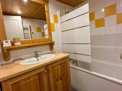 une salle de bain avec un lavabo, un miroir et une baignoire dans l'établissement Appartement confortable avec mezzanine, terrasse et casier à ski aux pieds des pistes - FR-1-351-236, à La Plagne Tarentaise