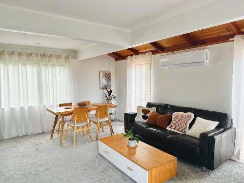 a living room with a black couch and a table at Private room with separate bathroom and carpark in Auckland