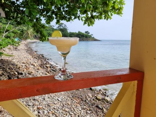 a martini glass sitting on a railing overlooking the ocean at Cabañas y Restaurante Miss Elma in Providencia