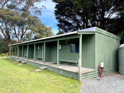 a green modular building with a wooden porch at Pukenui Holiday Park in Pukenui