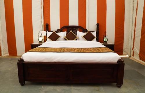 a bedroom with a bed with orange and white stripes at Golden Heaven Desert Camp in Jaisalmer