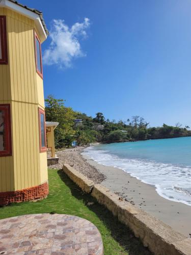 a yellow building next to a beach with the ocean at Cabañas y Restaurante Miss Elma in Providencia