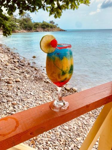 a drink with a fruit in it sitting on a rail near the water at Cabañas y Restaurante Miss Elma in Providencia