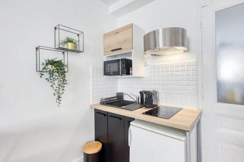une cuisine avec un évier et un micro-ondes dans l'établissement Le Cosy ,3 mn de la gare ,Vincennes Porte de Paris, à Vincennes