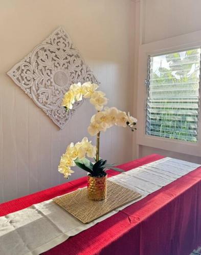 a table with a vase with flowers on it at YOUR PERFECT HILO HOMEBASE - Sleeps 10 with AC, WD, BBQ in Hilo