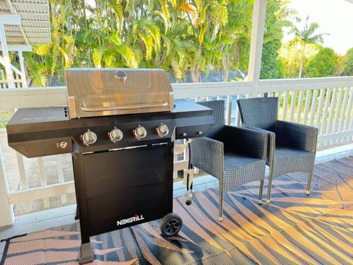 a barbecue grill on a porch with two chairs at YOUR PERFECT HILO HOMEBASE - Sleeps 10 with AC, WD, BBQ in Hilo