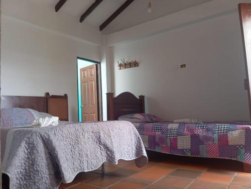 a bedroom with two beds and a door to a room at Cabaña Cueva del Zorro in Ráquira