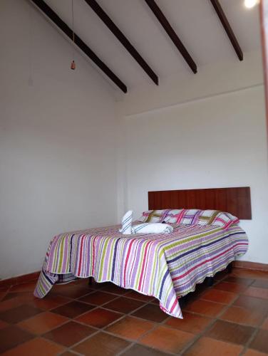a bed in a room with a striped blanket on it at Cabaña Cueva del Zorro in Ráquira