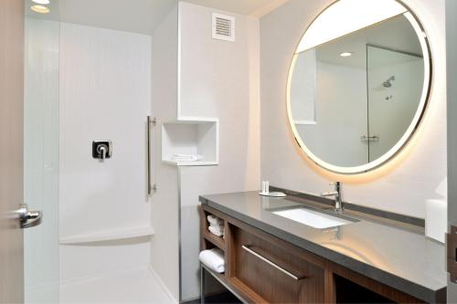 a bathroom with a sink and a mirror at Courtyard by Marriott Raleigh Cary Crossroads in Cary